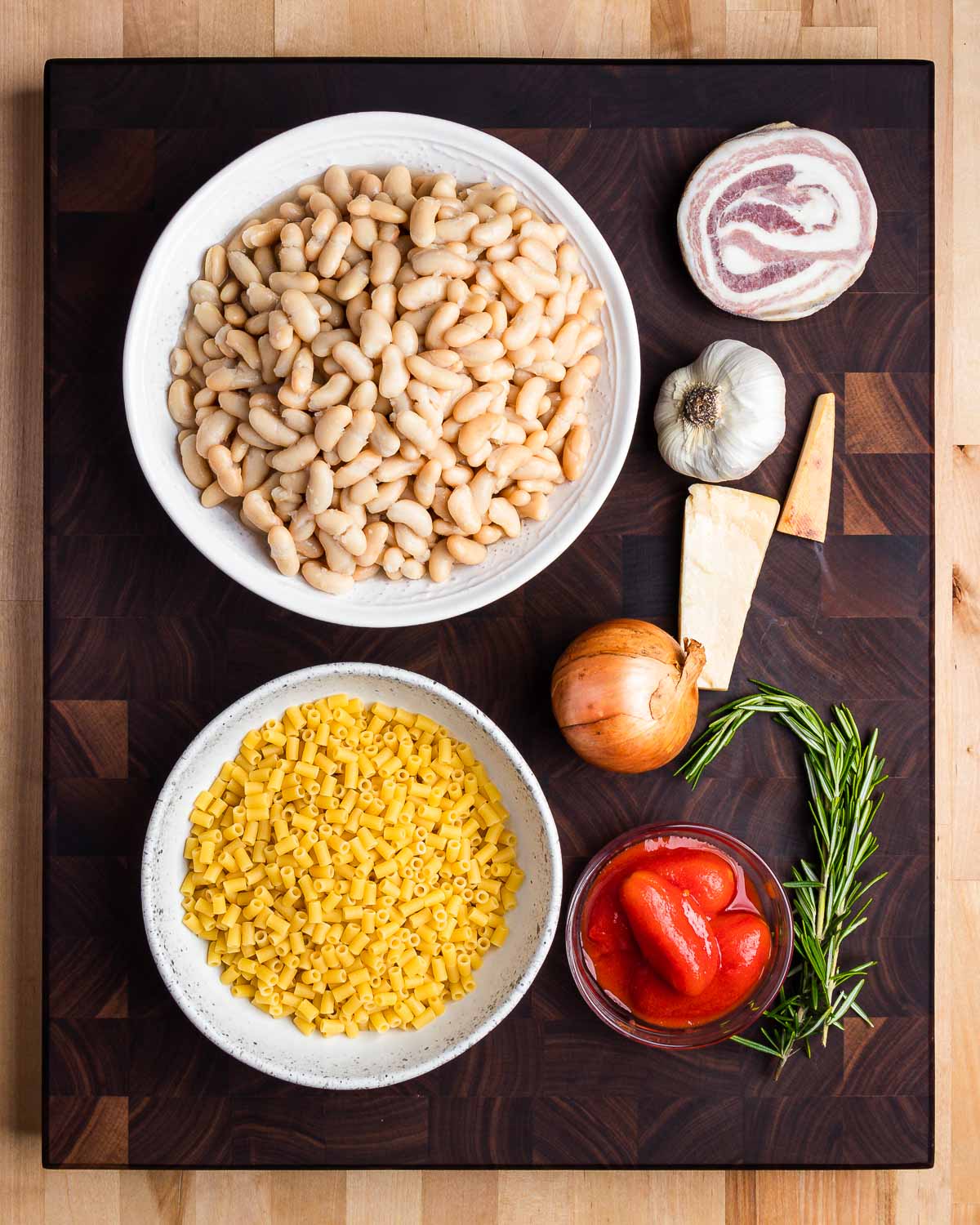 Ingredients shown: cannellini beans, pancetta, garlic, Parmigiano rinds, onion, ditalini pasta, plum tomatoes, and rosemary sprig.