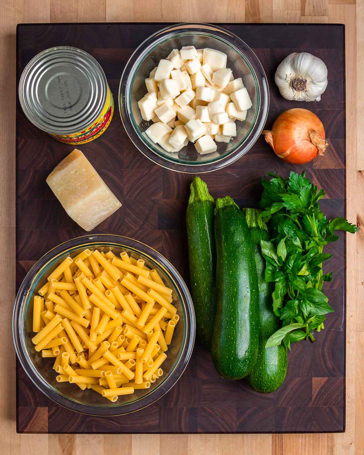 Ingredients shown: plum tomatoes, mozzarella, garlic, onion, Pecorino, ziti, zucchini, basil, and parsley.