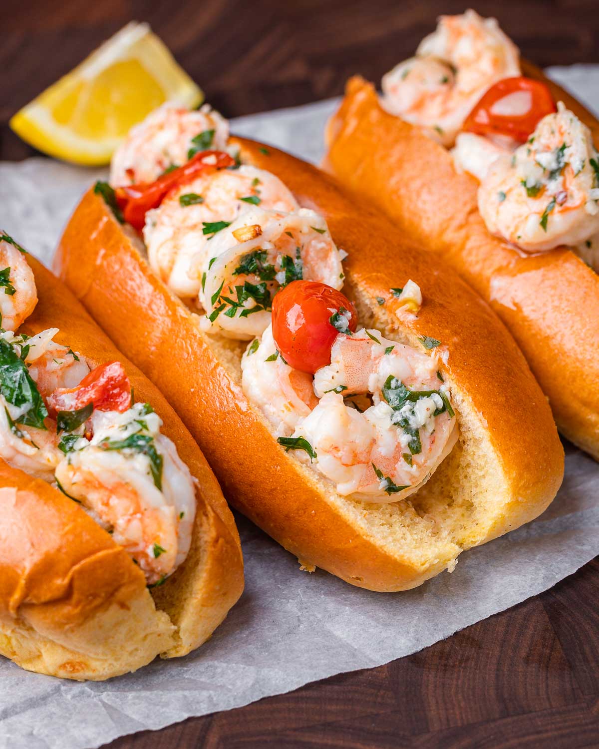 Three shrimp scampi rolls on paper.