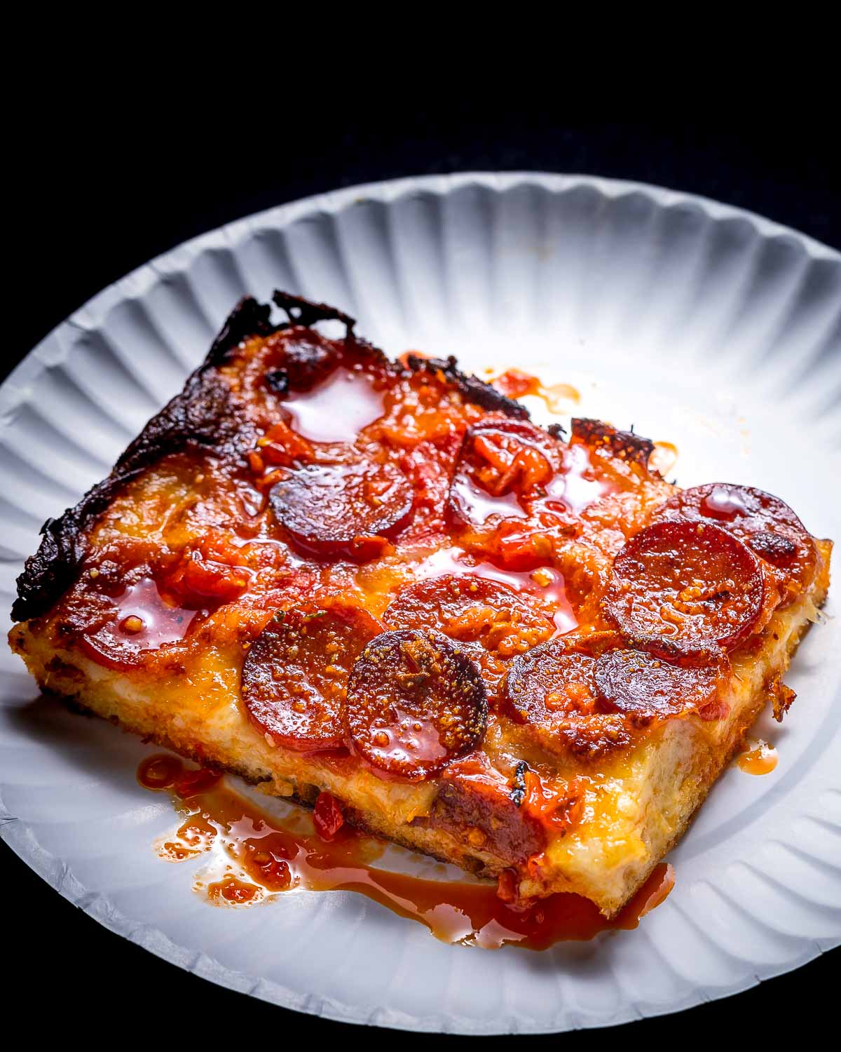 Pepperoni pizza slice in white plate.