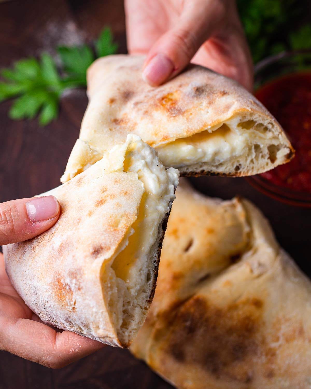Hands holding cut in half calzone.