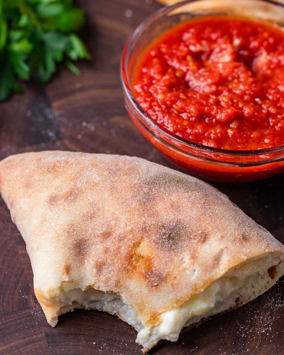 Half of calzone with a bite taken out of it.