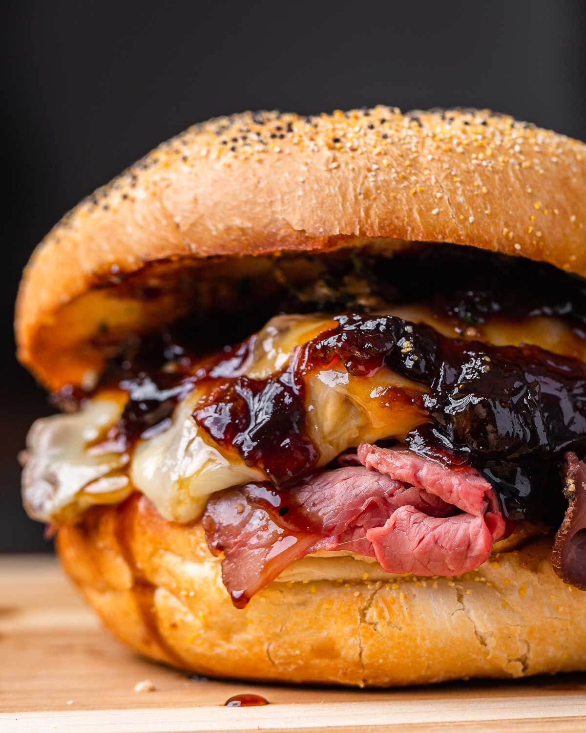 Closeup shot of roast beef sandwich with onion jam on cutting board.