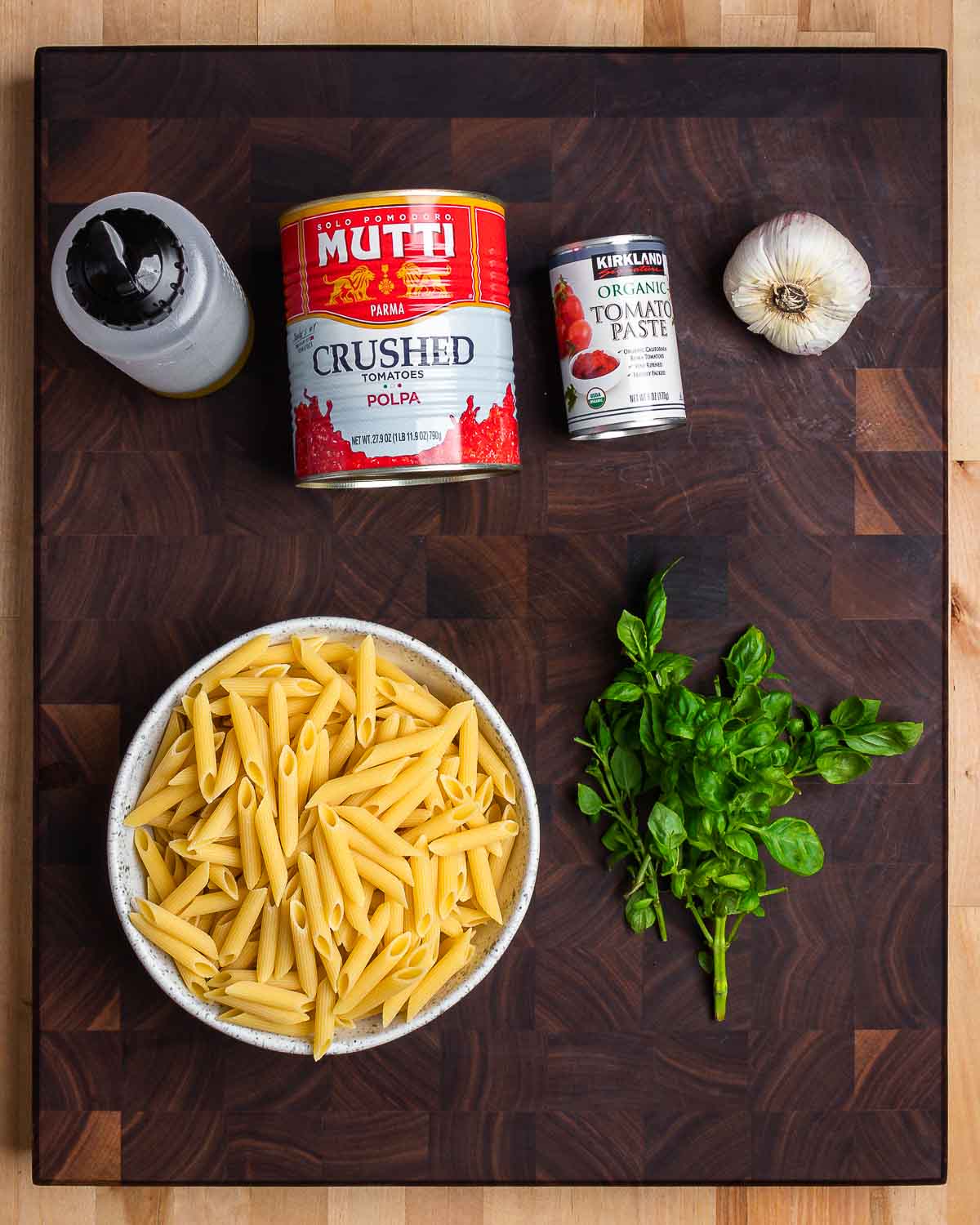 Ingredients shown: olive oil, plum tomatoes, tomato paste, garlic, penne pasta, and basil.