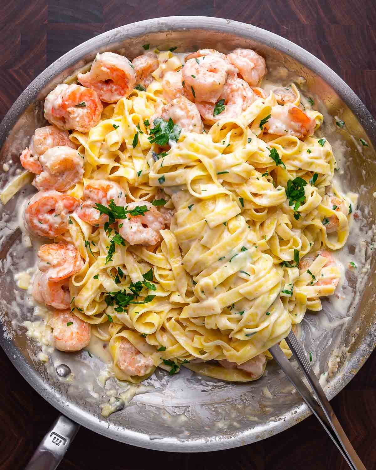 Shrimp Alfredo in pan on walnut cutting board.