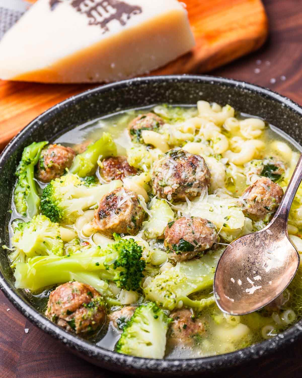 Black bowl with macaroni, broccoli, and tiny meatballs.