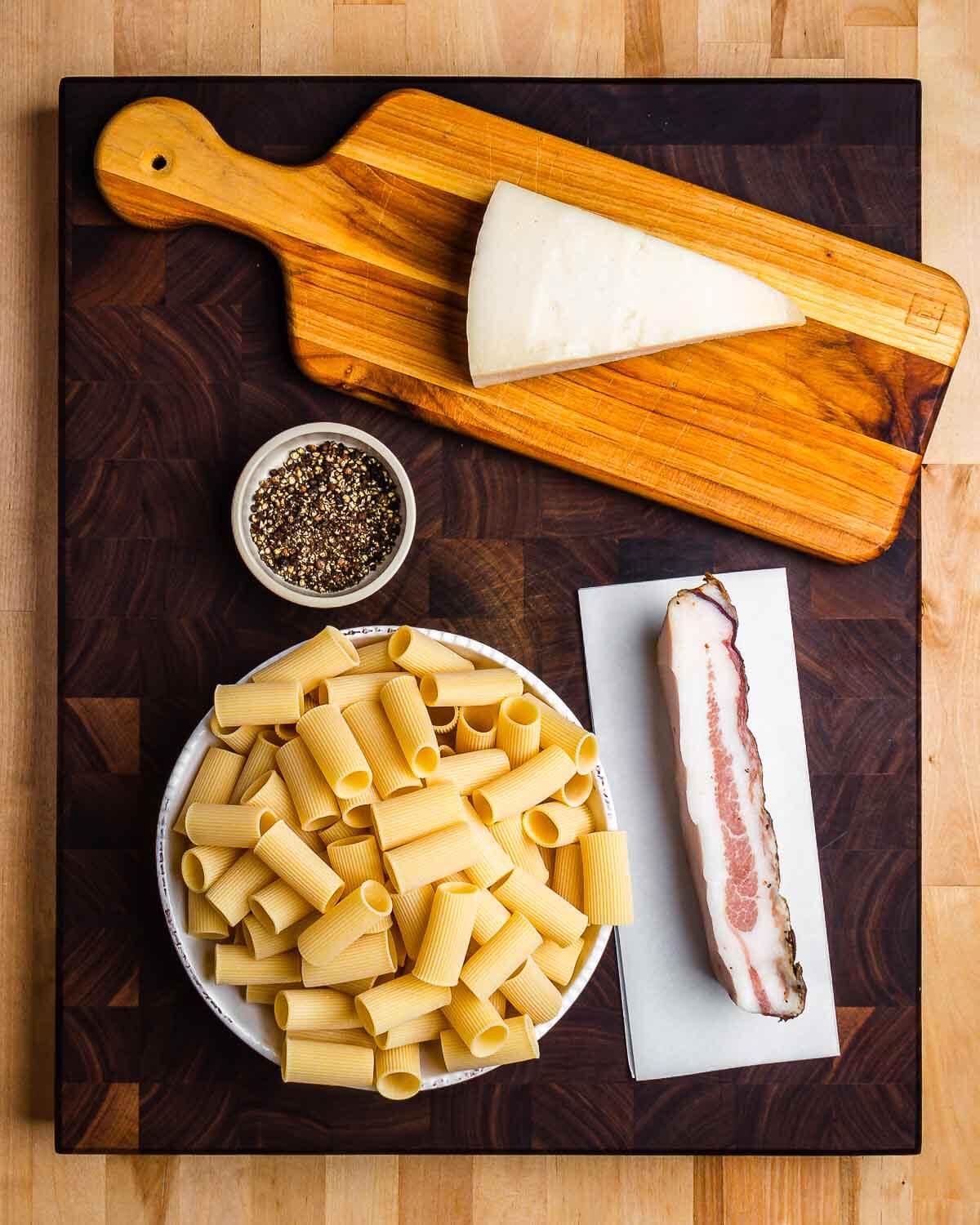 Ingredients shown: Pecorino Romano, pepper, rigatoni, and guanciale.