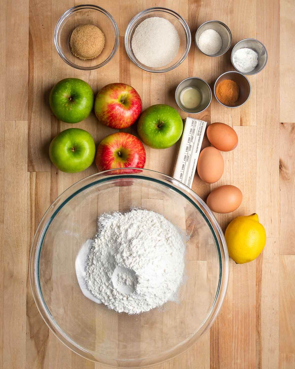 Ingredients shown: brown sugar, sugar, cinnamon, baking powder, baking soda, vanilla extract, apples, eggs, butter, lemon, and flour.