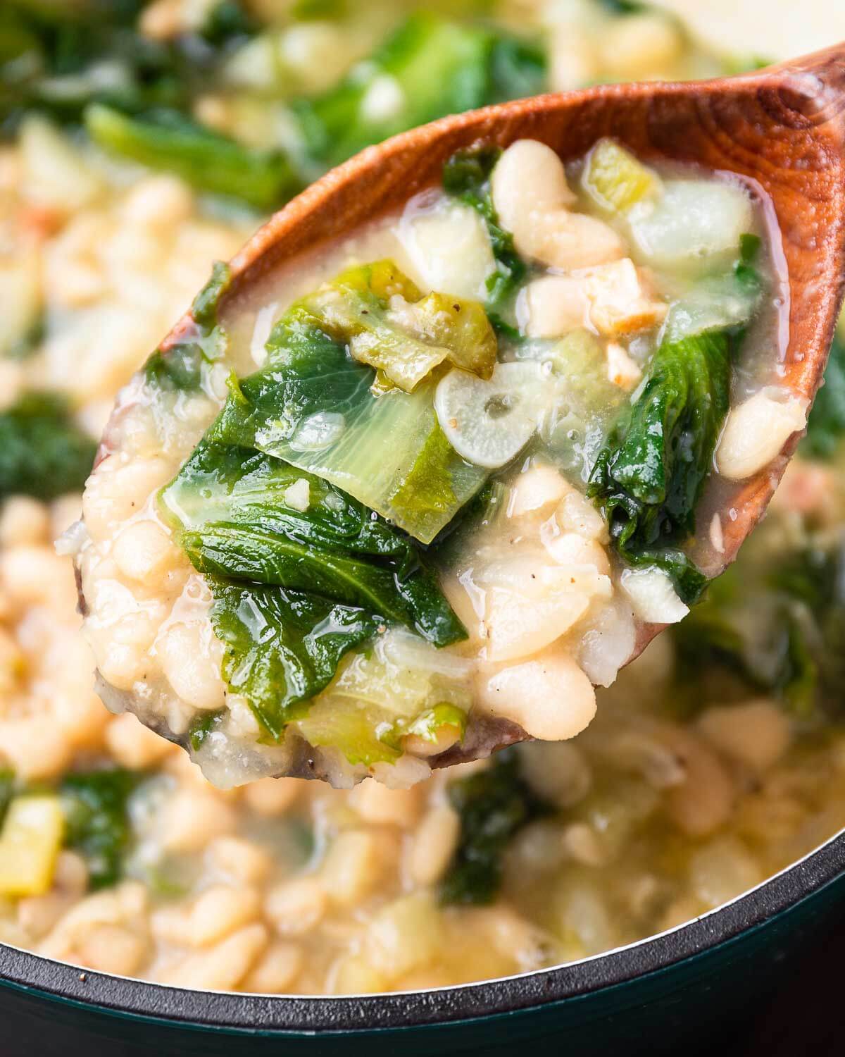 Large wooden ladle with escarole and white bean soup.