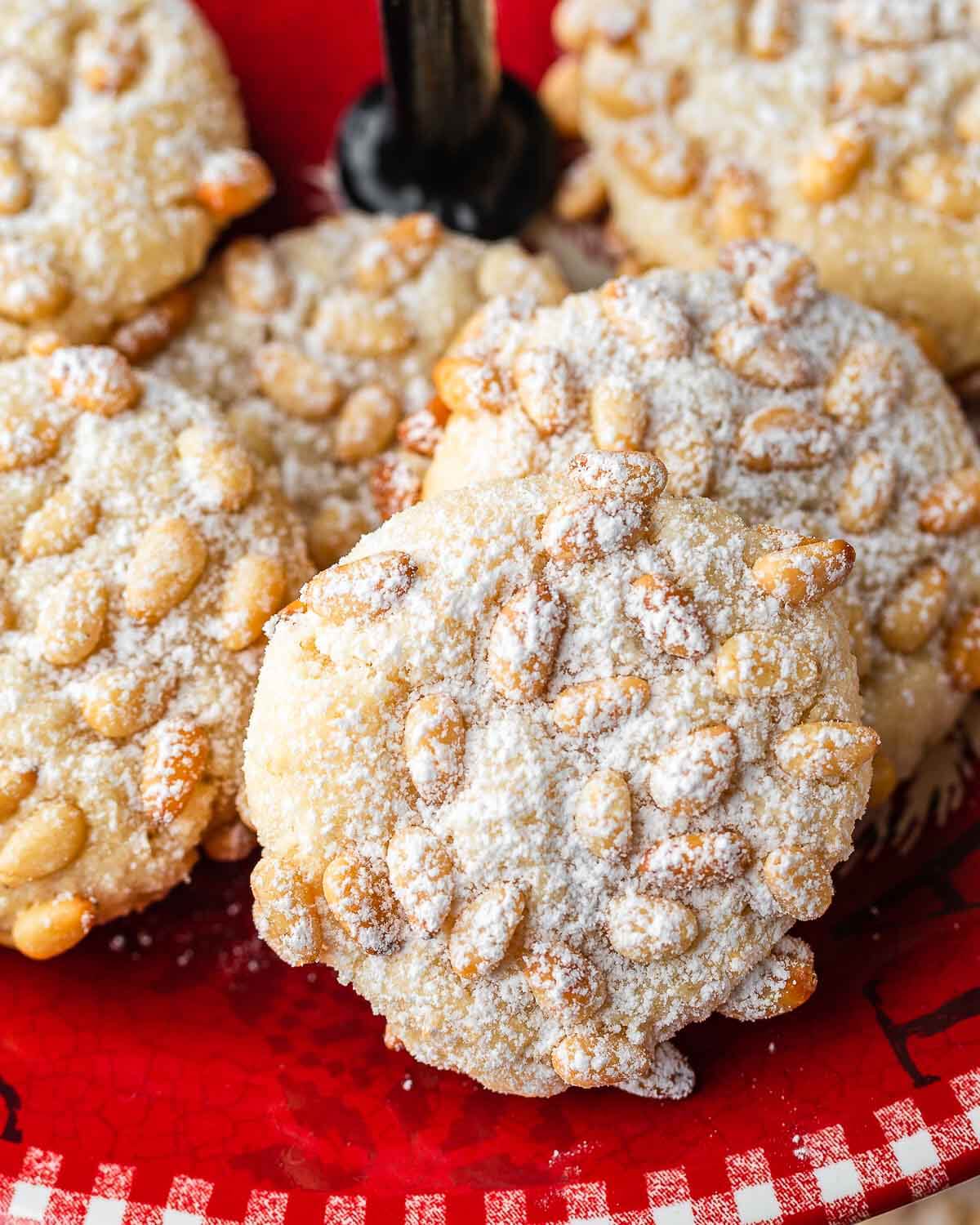 Pignoli cookies on red plate.