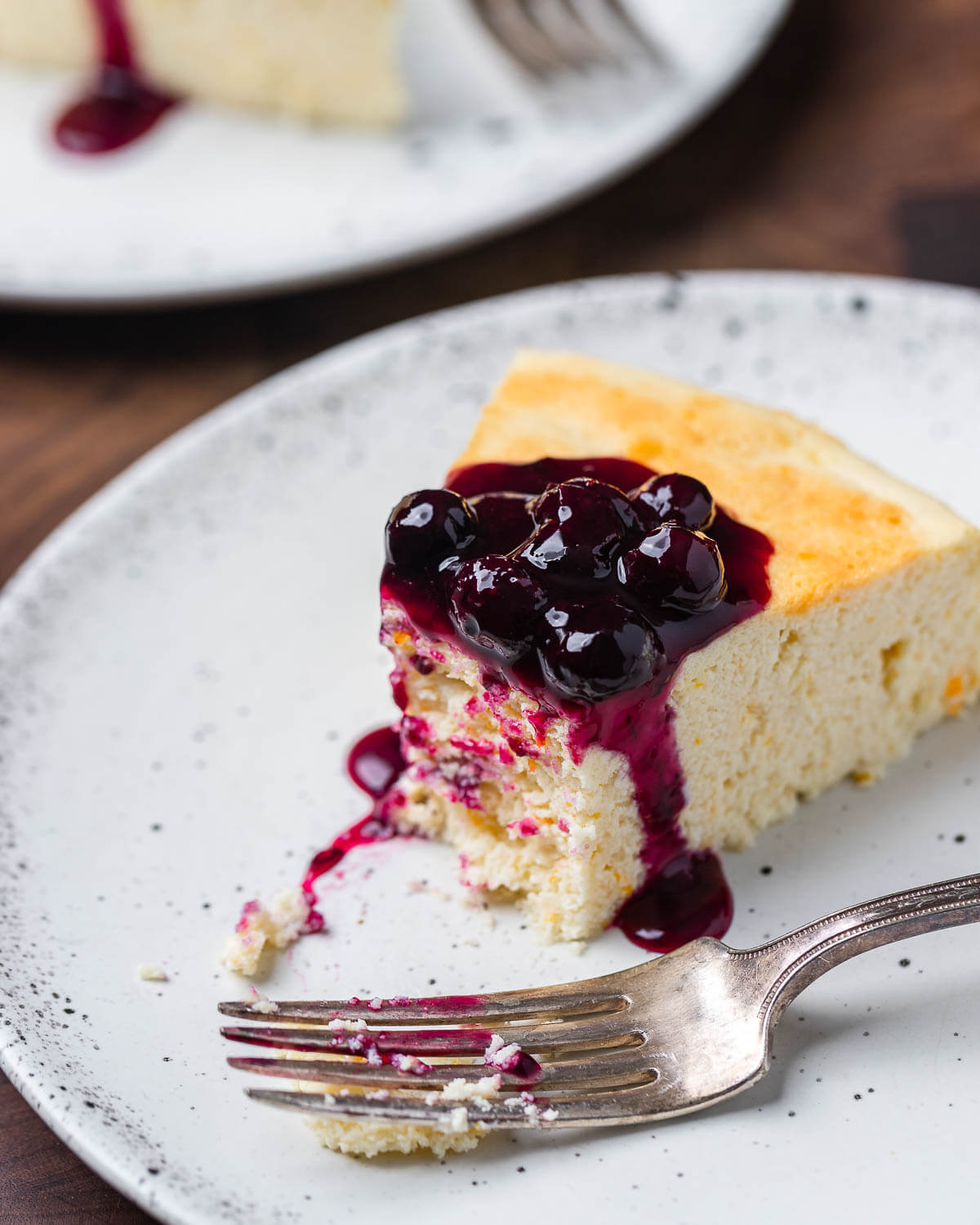 Italian cheesecake slice with bite taken out of it on white plate.