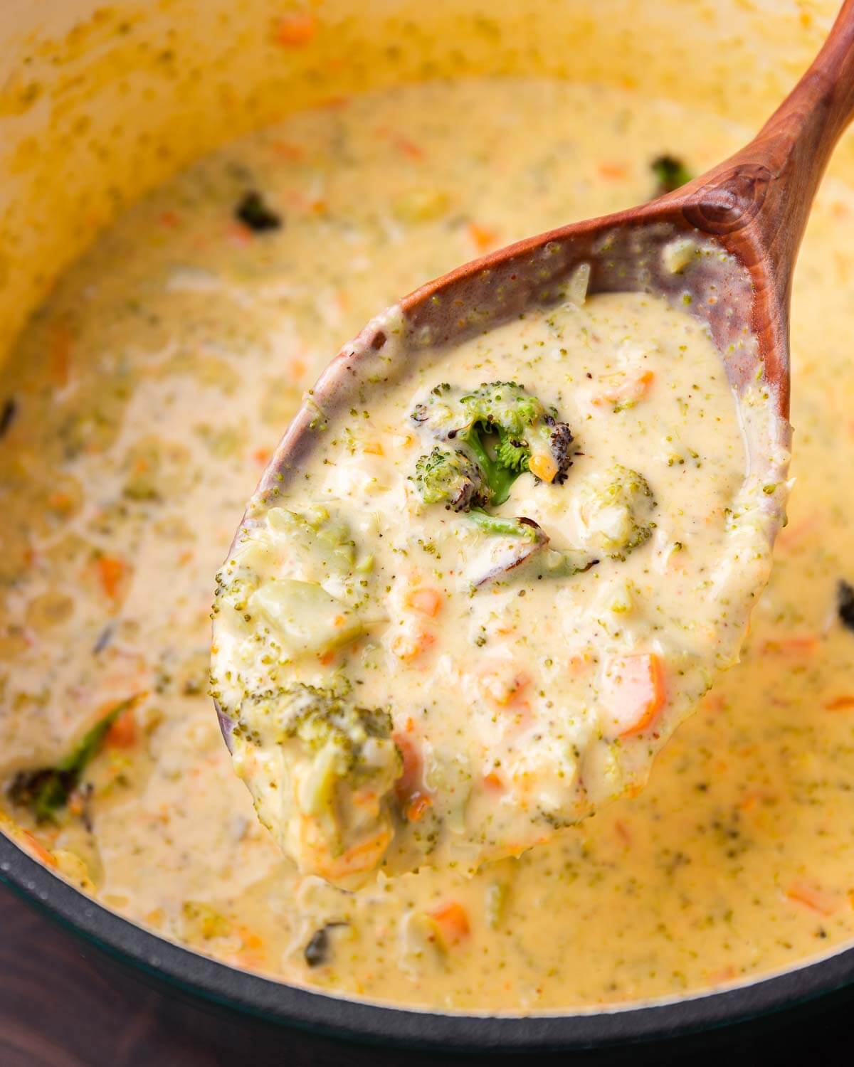 Large wooden ladle with broccoli cheddar soup.