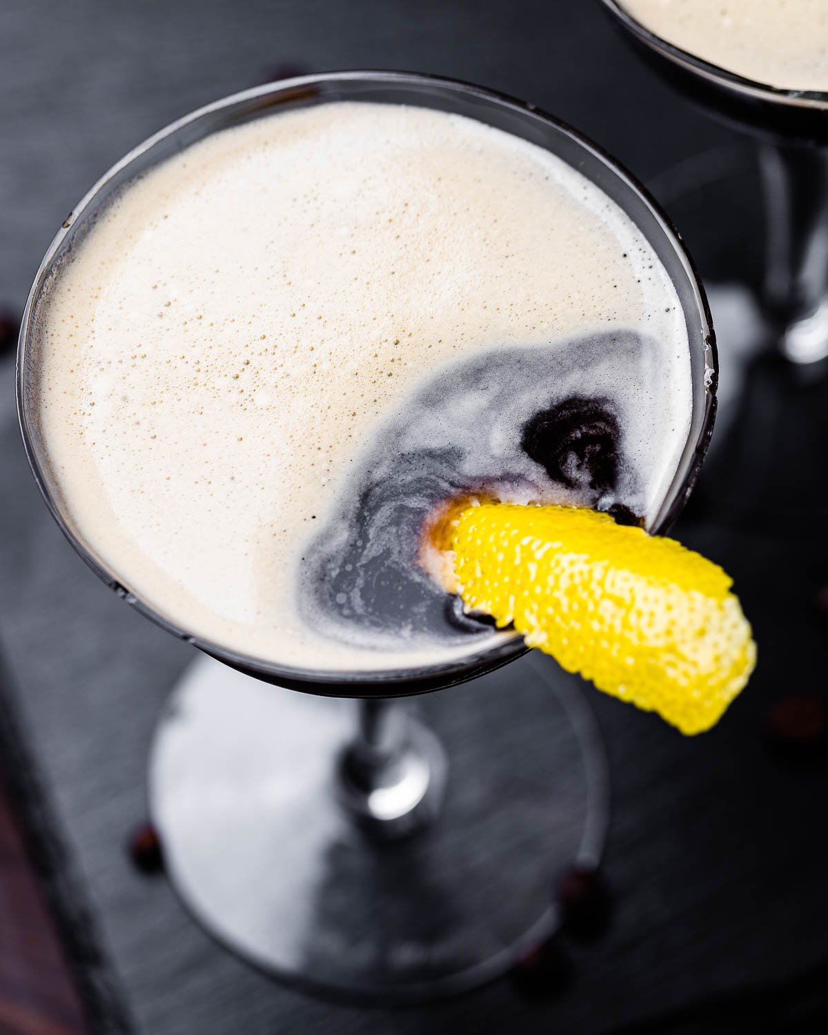 Overhead shot of espresso martini on black slate board.