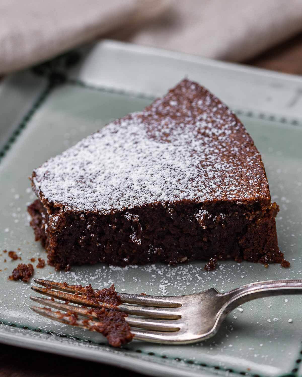 Slice of flourless chocolate cake with bite taken out of it.