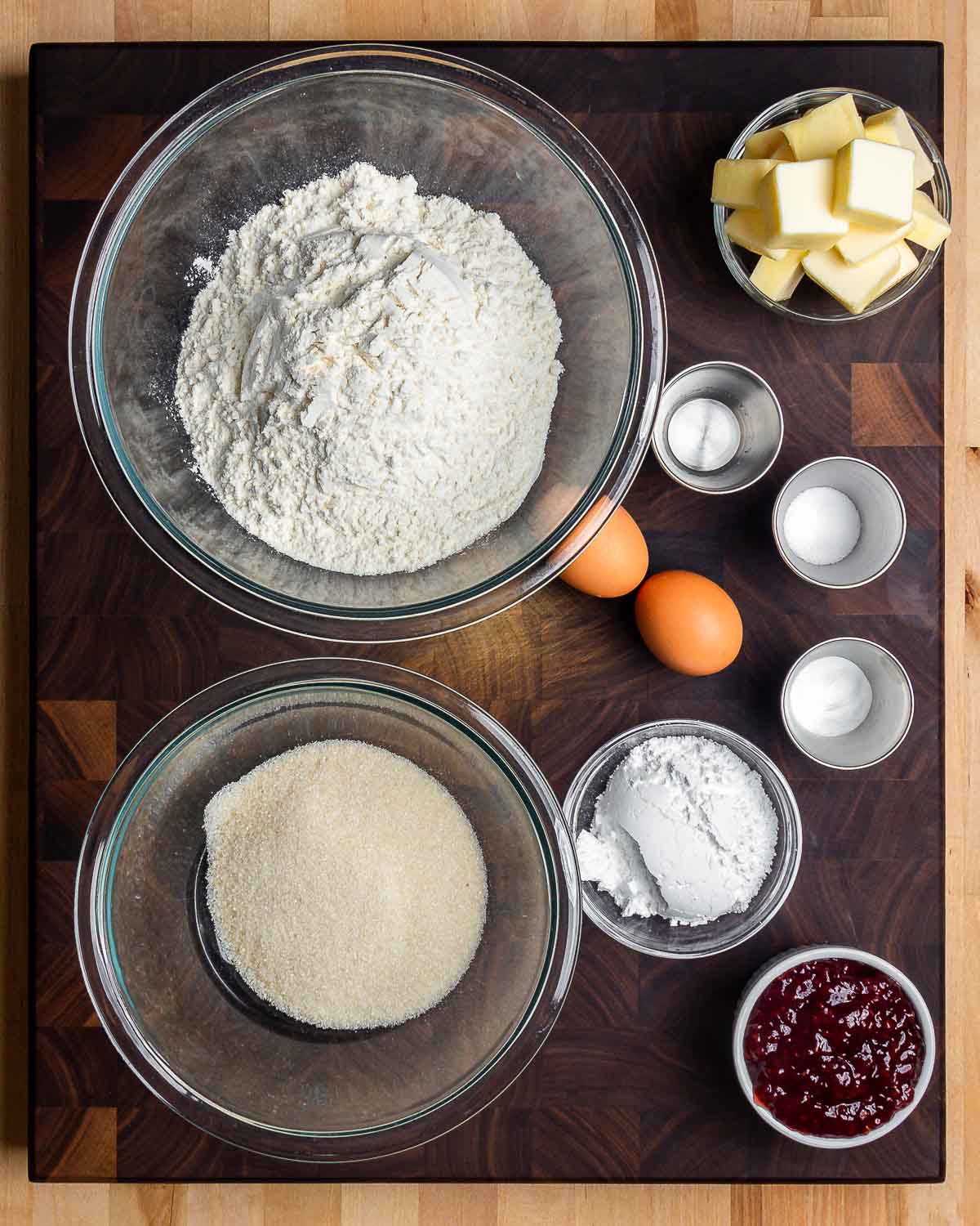 Ingredients shown: flour, butter, almond extract, salt, eggs, baking powder, sugar, powdered sugar, and raspberry jam.
