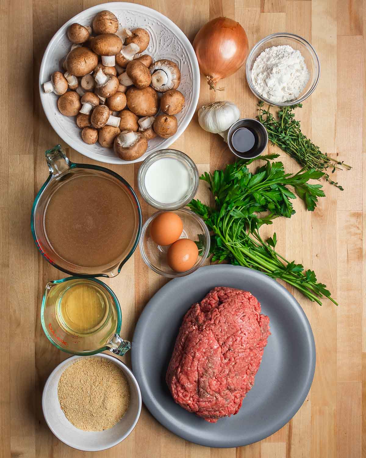 Ingredients shown: mushrooms, onion, flour, garlic, worcestershire sauce, thyme, parsley, beef stock, milk, eggs, white wine, breadcrumbs, and ground beef.