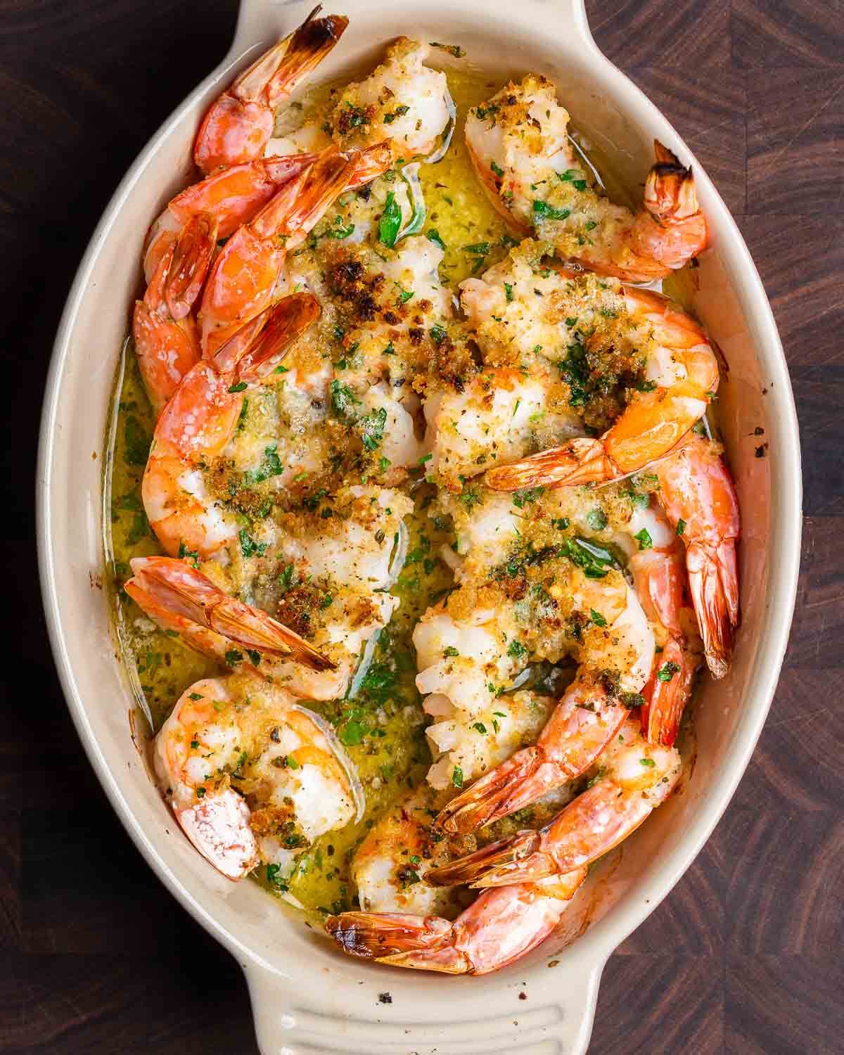 Overhead shot of shrimp oreganata on walnut cutting board.