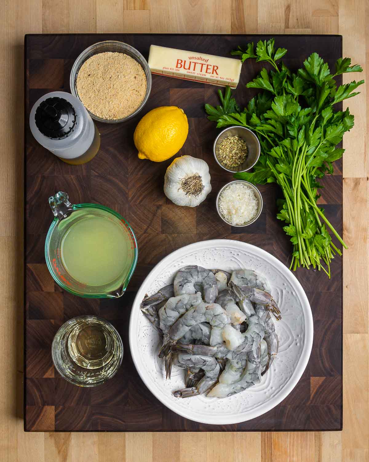 Ingredients shown: breadcrumbs, olive oil, lemon, garlic, parmesan, oregano, parsley, chicken stock, white wine, and shrimp.