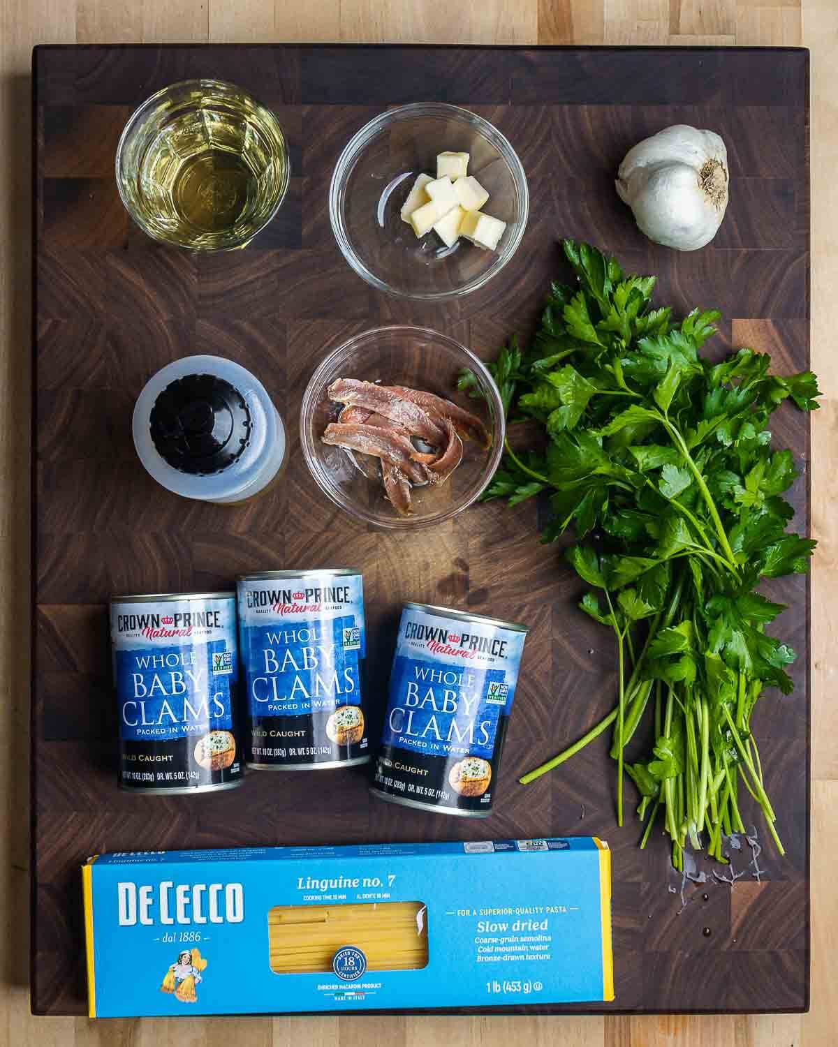 Ingredients shown: white wine, butter, garlic, olive oil, anchovies, parsley, canned clams, and linguine.