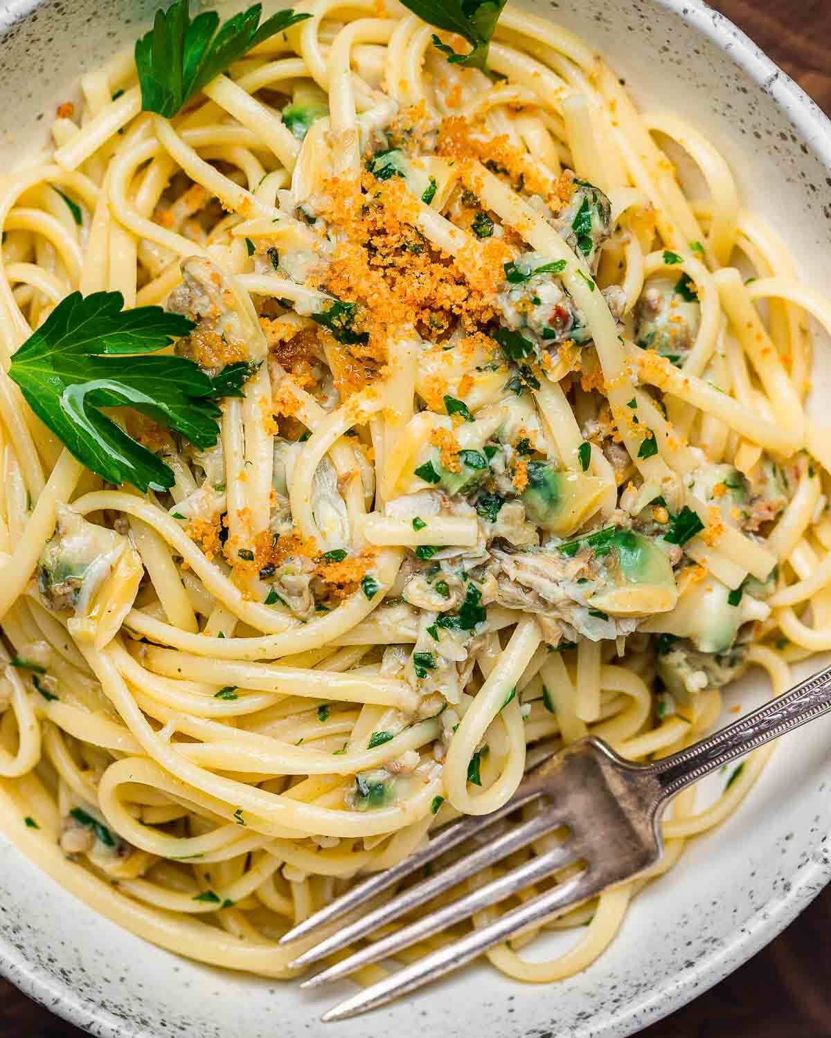 Bowl of linguine with canned clam sauce topped with seasoned breadcrumbs.