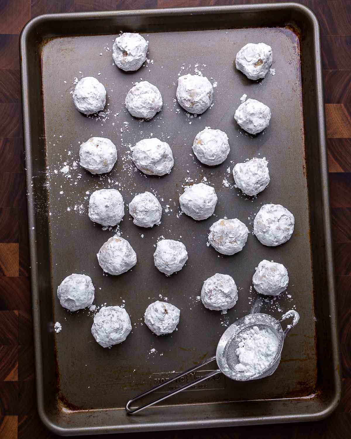 Overhead shot of baking tray filled with walnut snowball cookies.