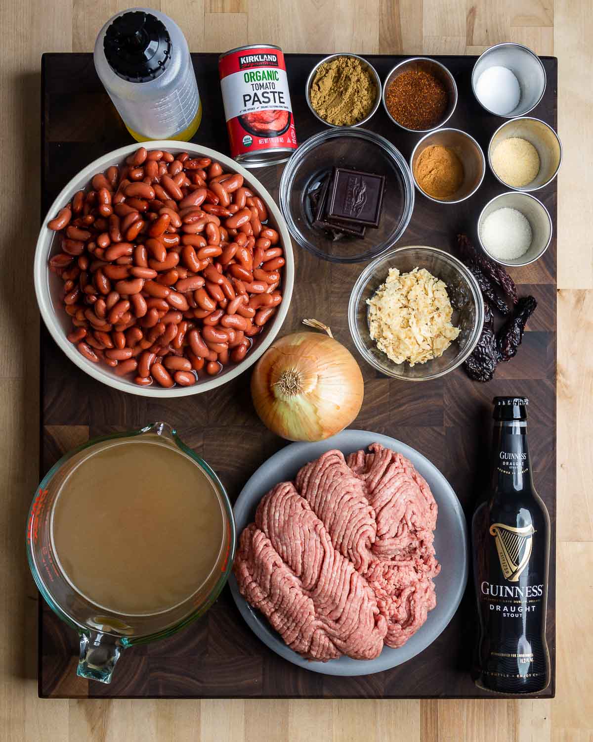 Ingredients shown: vegetable oil, tomato paste, dark chocolate, chile powder and spices, whole dried chiles, kidney beans, onion, tortilla chips, beef stock, ground chuck, and beer.