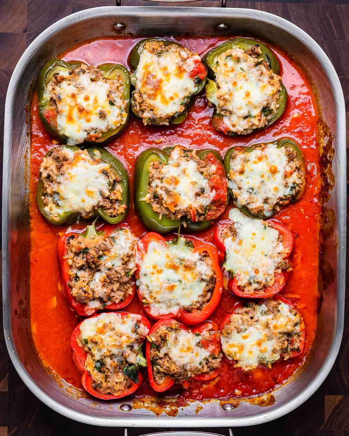 Overhead shot of baked Italian stuffed peppers in large roasting pan.