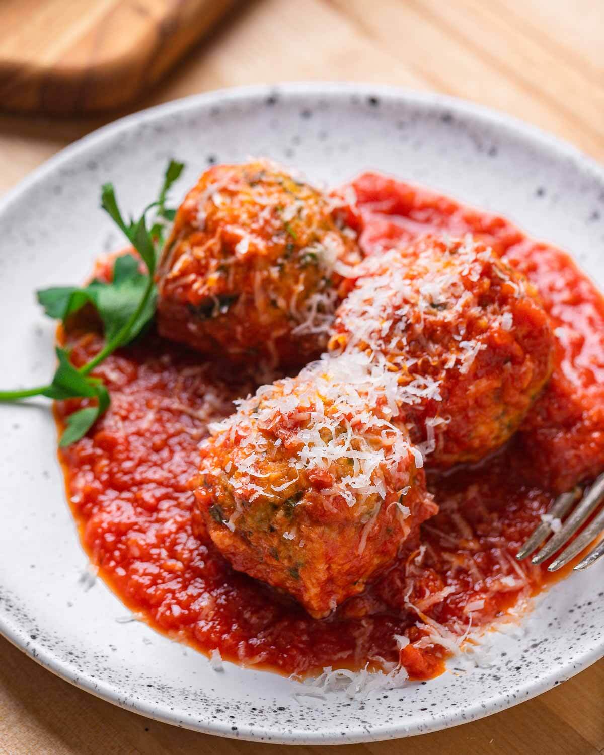 White plate with 3 meatless meatballs with grated cheese.