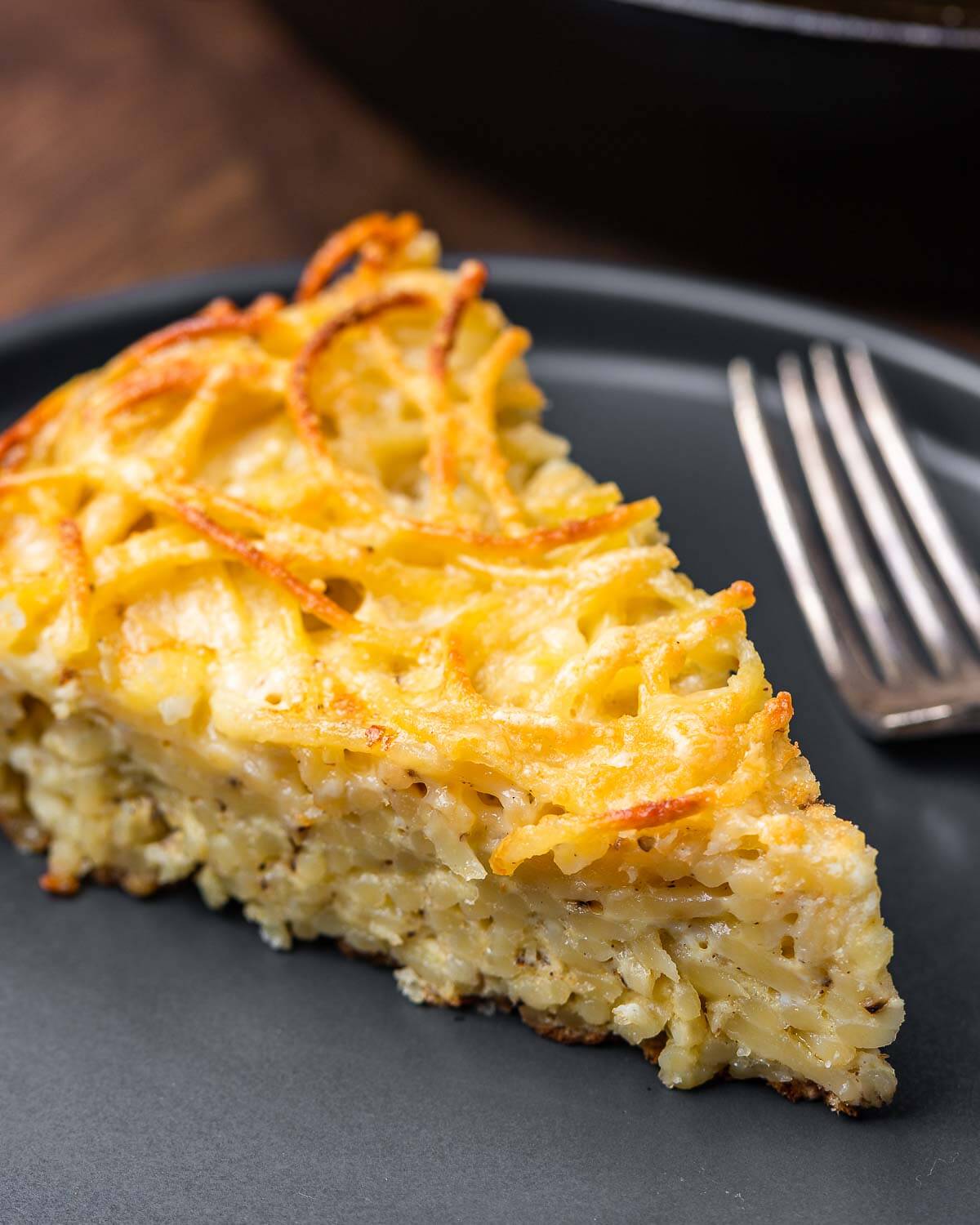 Slice of white spaghetti pie in grey plate.