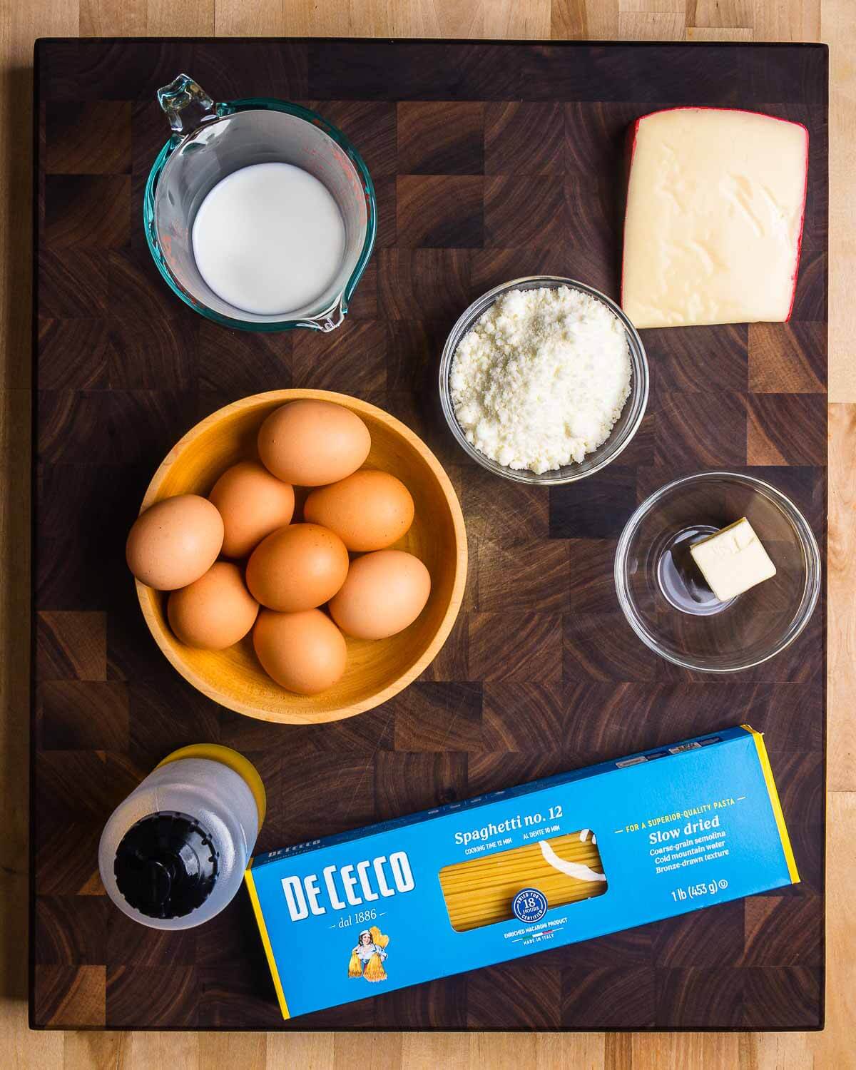 Ingredients shown: milk, fontina cheese, Pecorino Romano, eggs, butter, olive oil, and spaghetti.