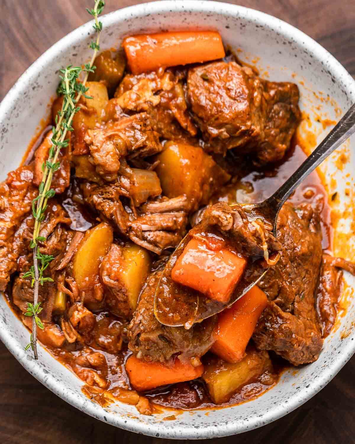 Ovehead shot of Guinness beef stew in white bowl with thyme garnish.