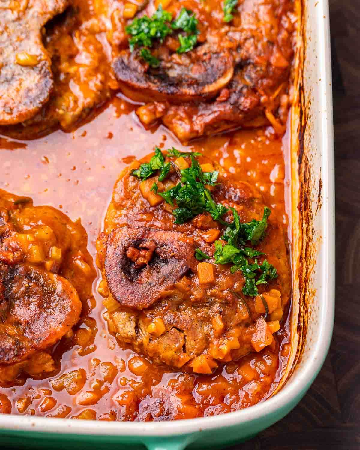 Large baking dish with veal osso buco topped with gremolata.