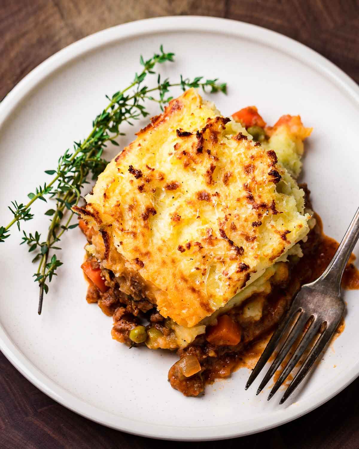 Ovehead shot of slice of shepherd's pie in white dish.