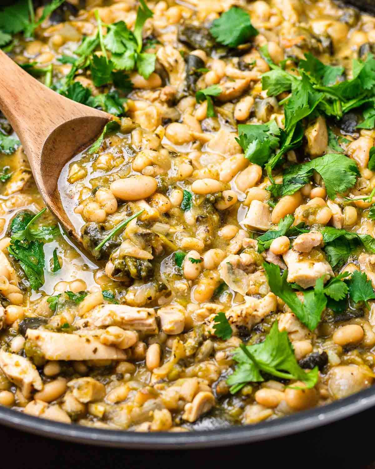 White chicken chili with cilantro in large black pan.