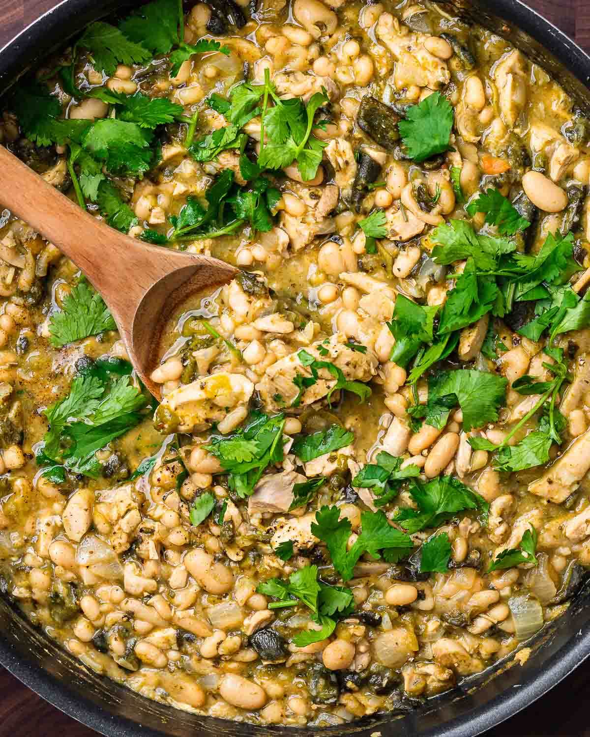 Overhead shot of white chicken chili with cilantro in large black pan.