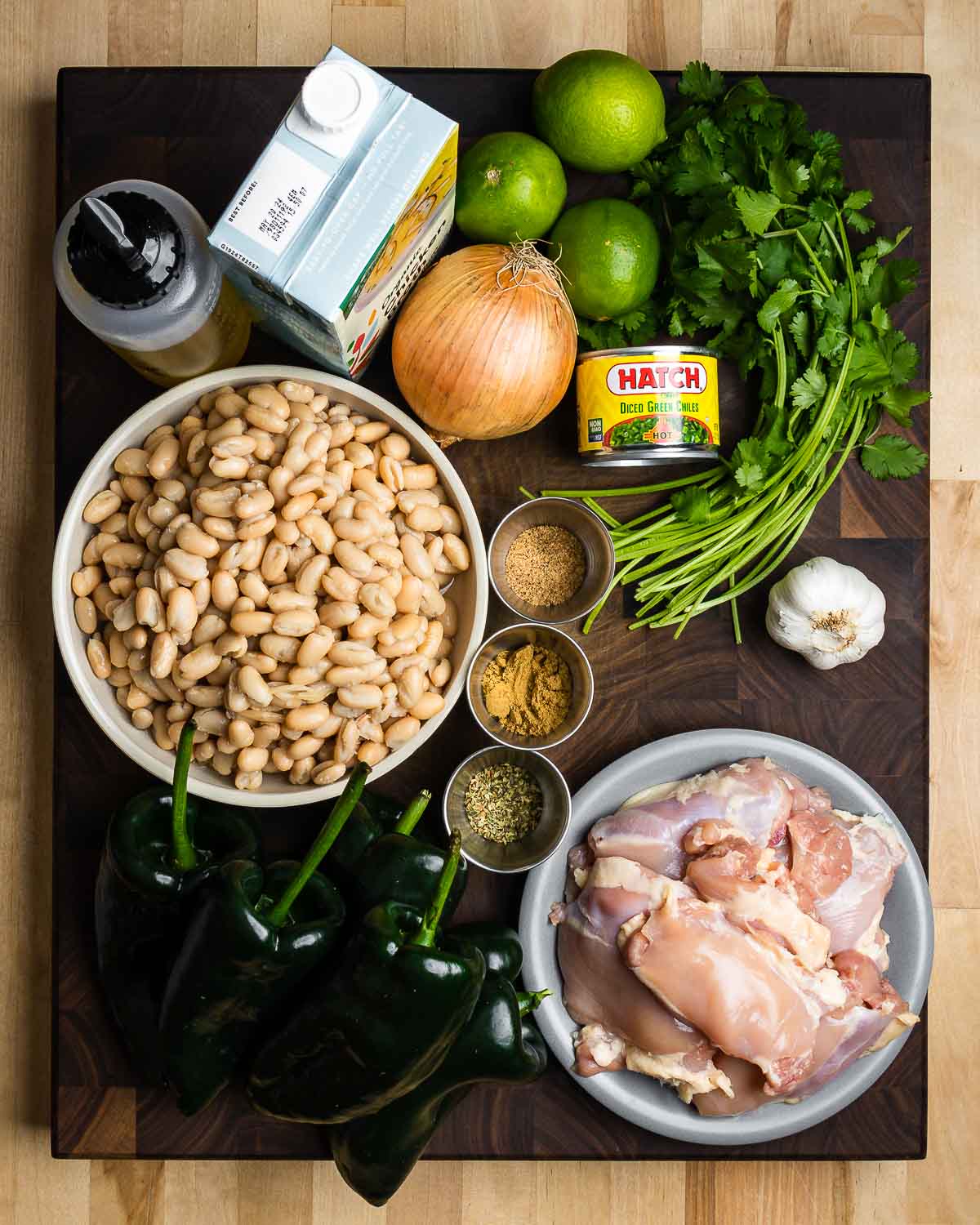 Ingredients shown: olive oil, chicken stock, onions, limes, cilantro, chiles, white beans, spices, garlic, and chicken thighs.