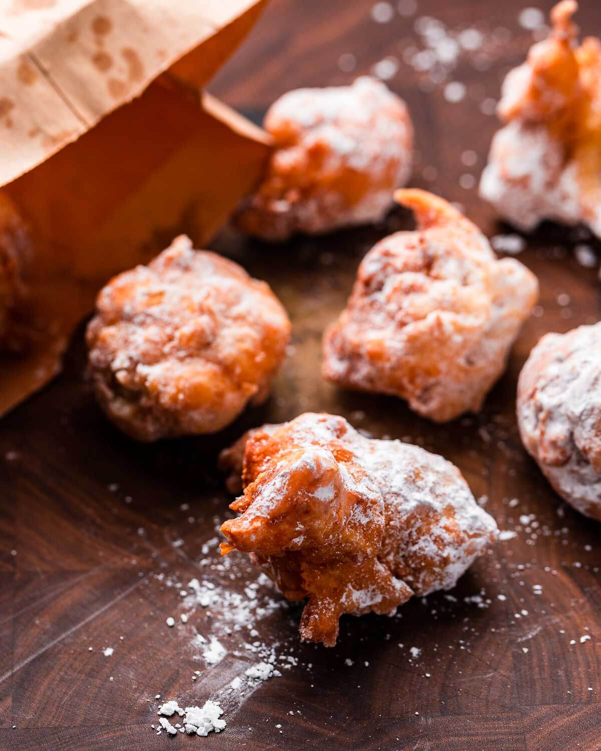 Zeppole on cutting board with brown paper bag.