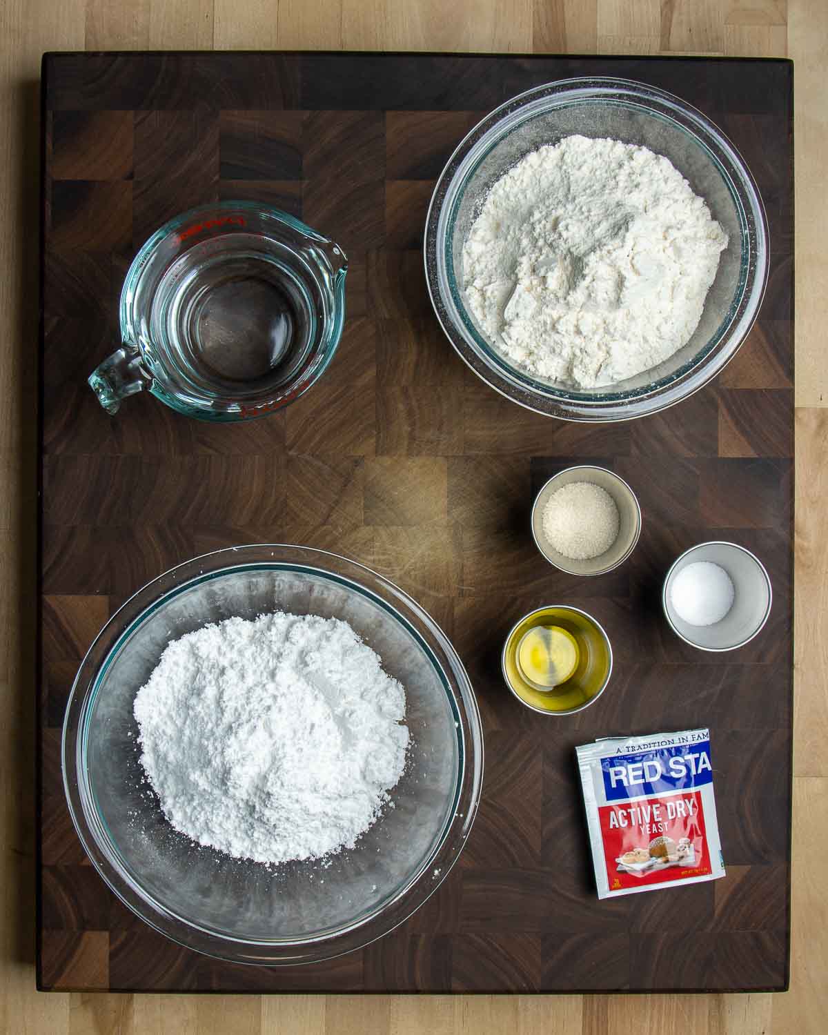 Ingredients shown: water, flour, powdered sugar, salt, sugar, olive oil, and yeast.