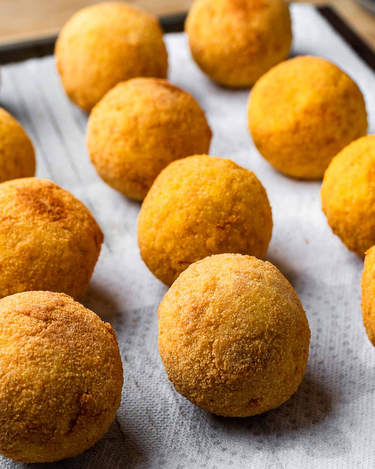 Pic of a bunch of fried arancini on white paper towels.