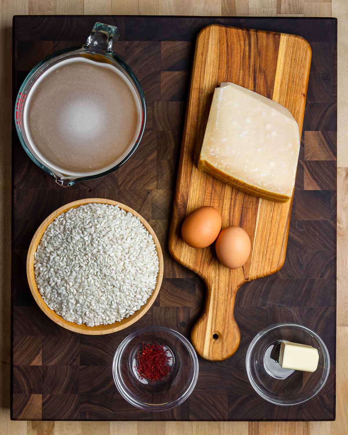 Ingredients shown: beef stock, Parmigiano Reggiano, eggs, arborio rice, saffron, and butter.