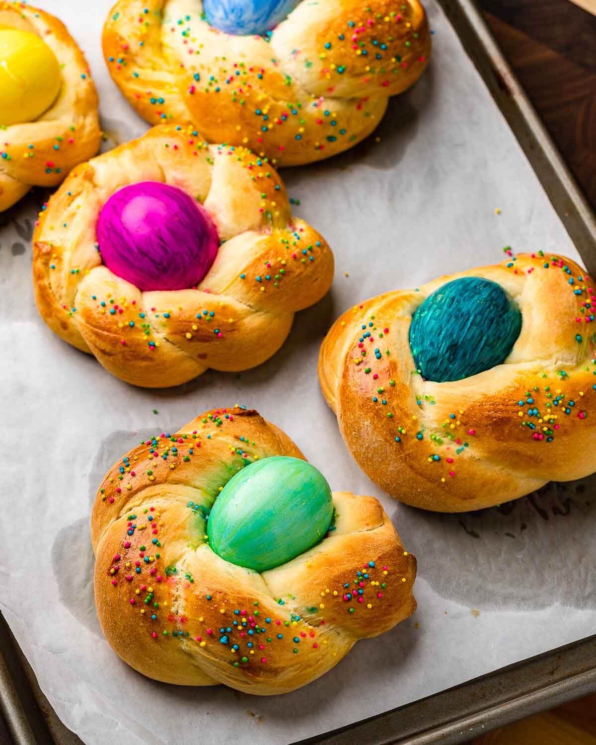 Parchment paper lined baking sheet with 5 Easter breads.