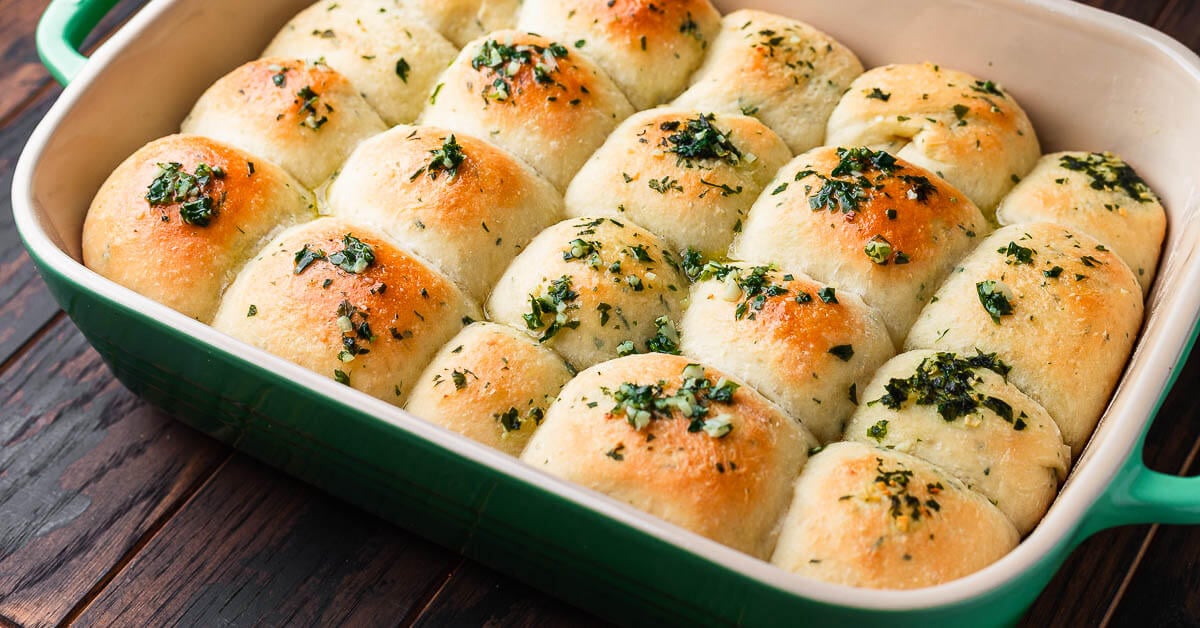 Fluffy garlic butter dinner rolls brushed with herb butter in a baking pan