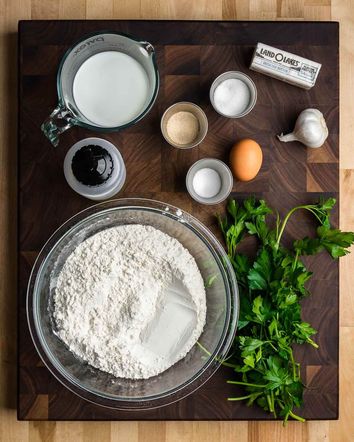 Ingredients shown: milk, yeast, salt, sugar, egg, butter, garlic, olive oil, bread flour, and parsley.