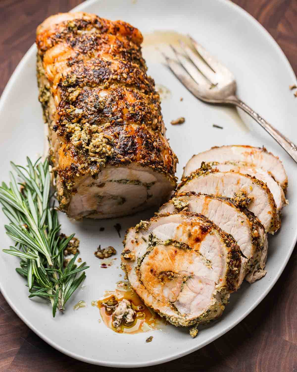 Overhead shot of Italian stuffed pork loin on a white platter.