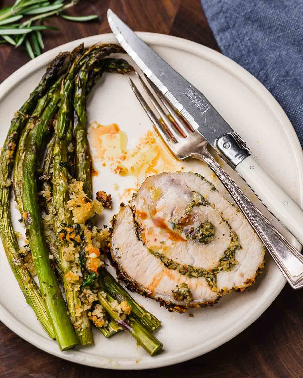 Overhead shot of stuffed pork loin and asparagus on white plate.