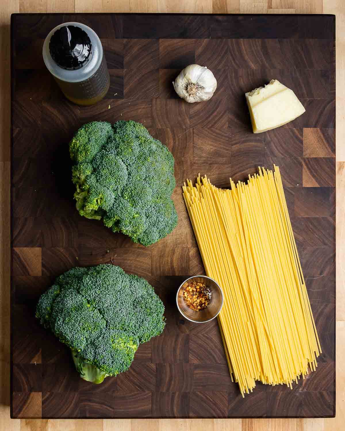 Ingredients shown: extra virgin olive oil, garlic, Pecorino Romano cheese, broccoli, hot red pepper flakes, and spaghetti.