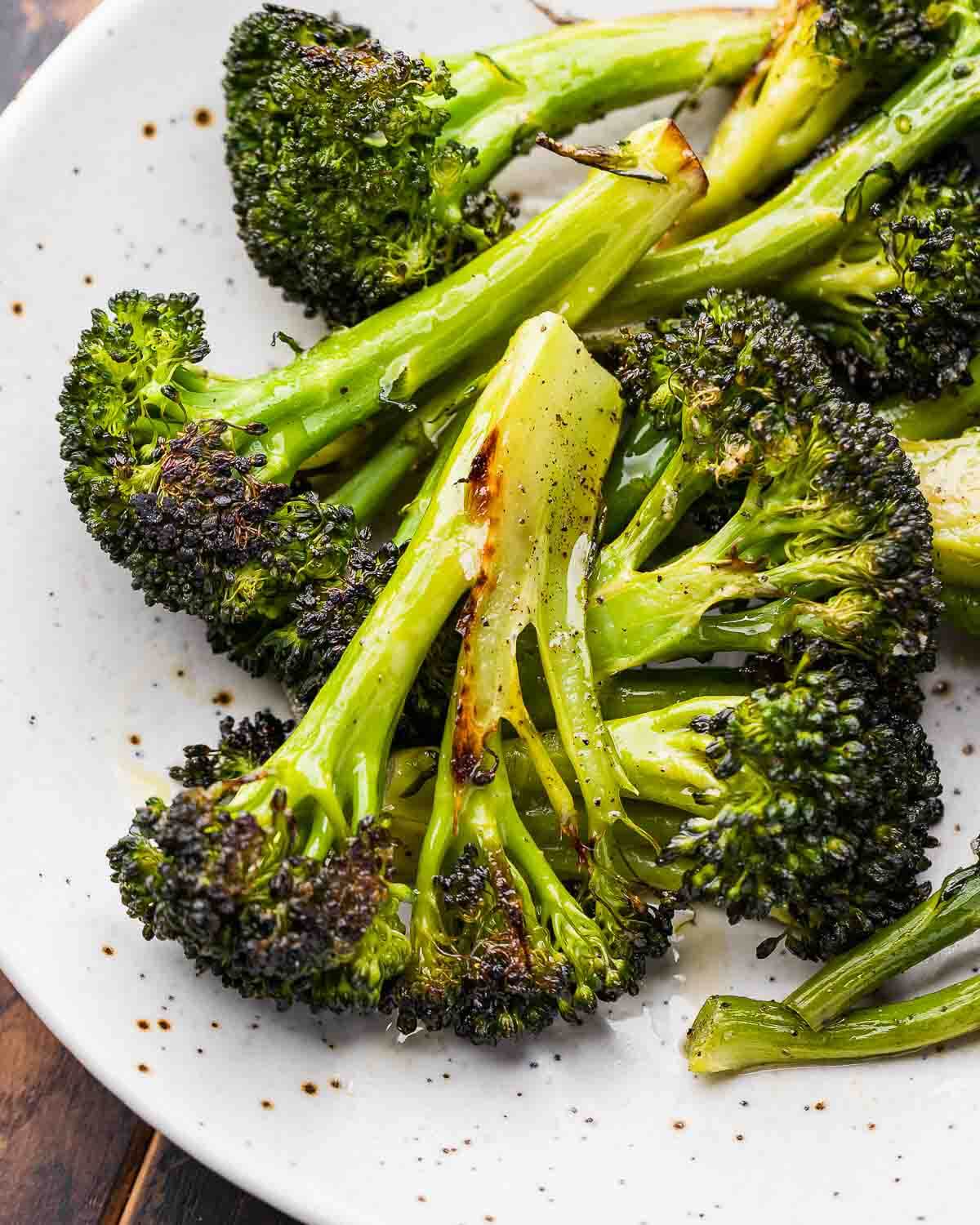 Closeup shot of roasted broccoli on white plate.