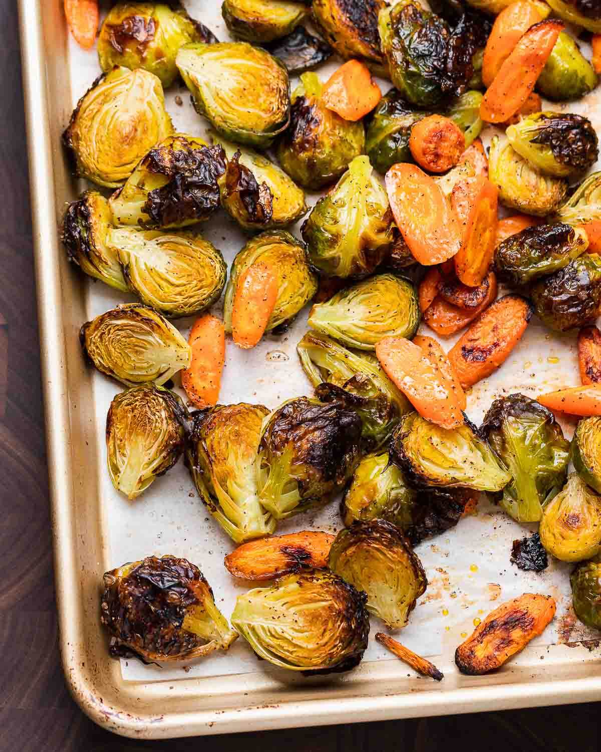 Closeup shot of roasted brussels sprouts and carrots in sheet pan.