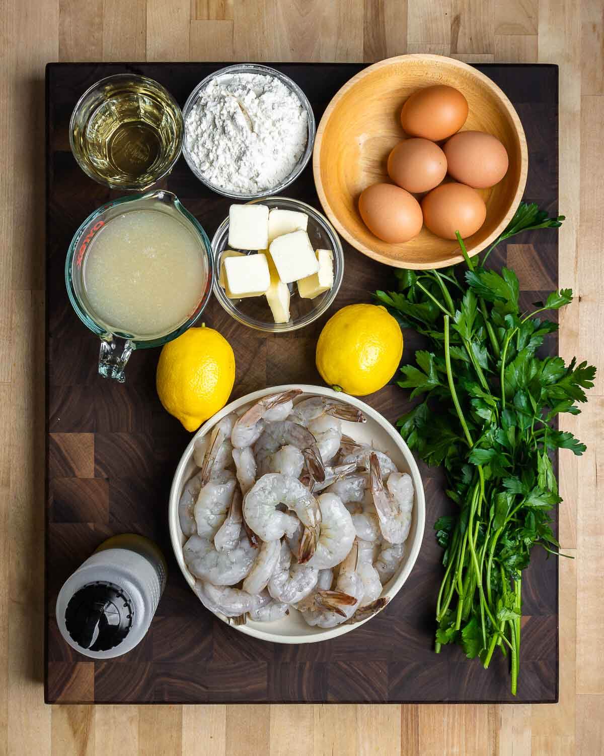 Ingredients shown: white wine, flour, eggs, chicken stock, butter, lemons, parsley, olive oil, and shrimp.