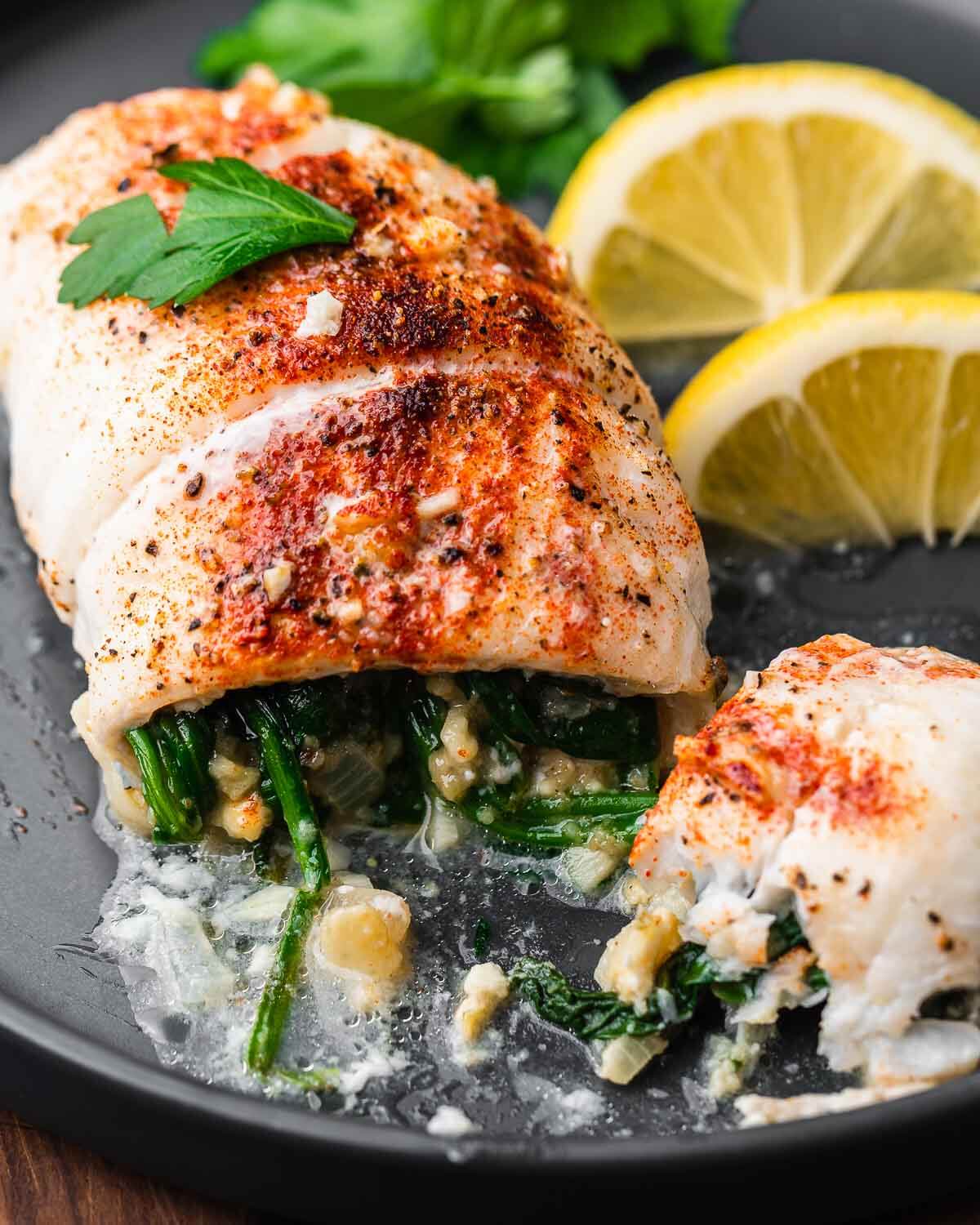 Cut open piece of spinach stuffed flounder on grey plate.